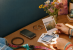 Hands sorting nostalgic printed photos beside an early smartphone and colorful friendship bracelets